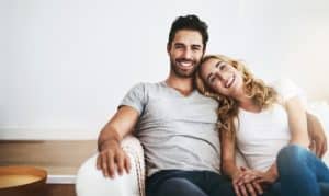 Beautiful couple smiling and sitting in the couch