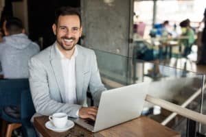 Handsome businessman using laptop at city cafe