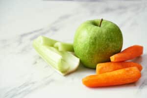 green apple carrots and celery on marble background