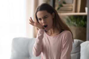 Woman holding jaw in pain from TMJ disorder