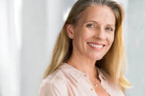 Mature woman shows off her new, natural-looking teeth after receiving dentures
