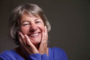 Senior citizen is excited by her own new perfect teeth with restorative dentistry
