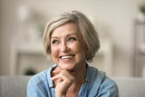 Senior woman with gray hair is pleased with her healthy teeth and dental implant