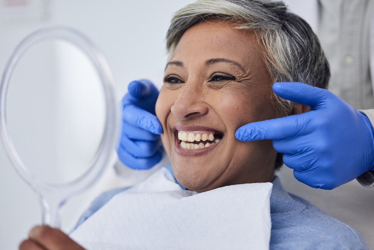 Woman is pleased with her new complete smile thanks to restorative dentistry.