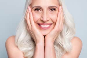 Woman smiles warmly, pleased with her dental implant outcome.